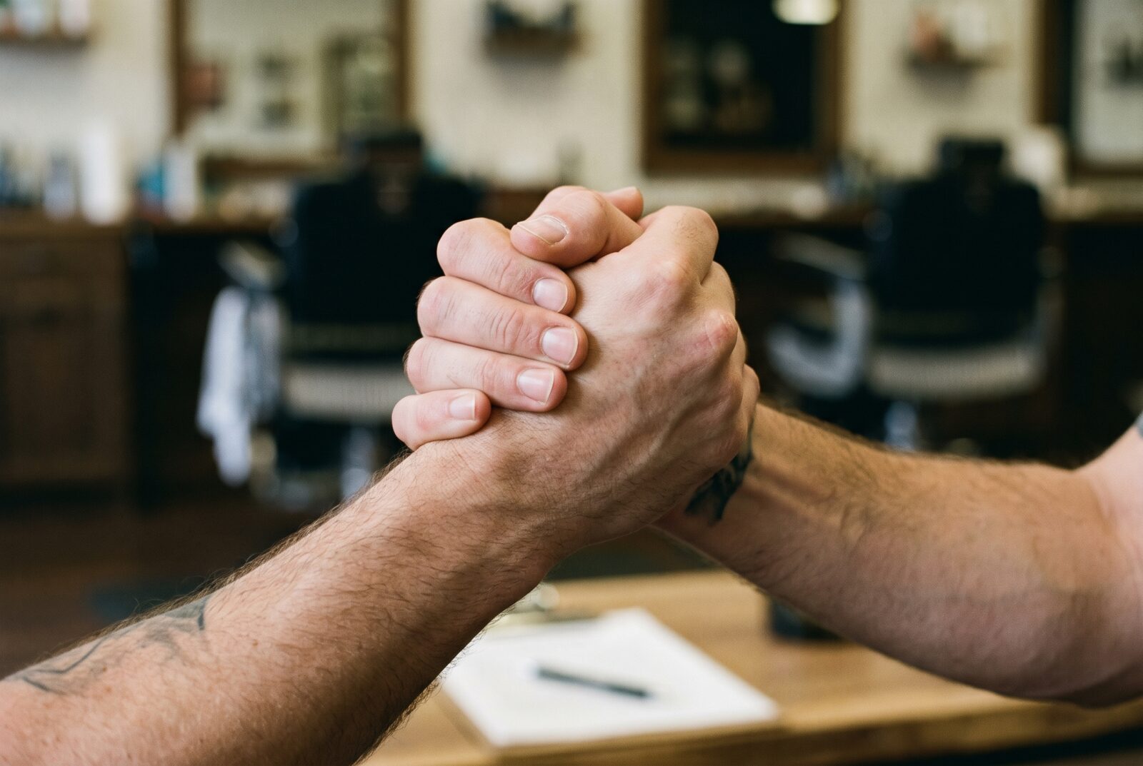 Aperto de mãos entre o dono da barbearia e o barbeiro parceiro