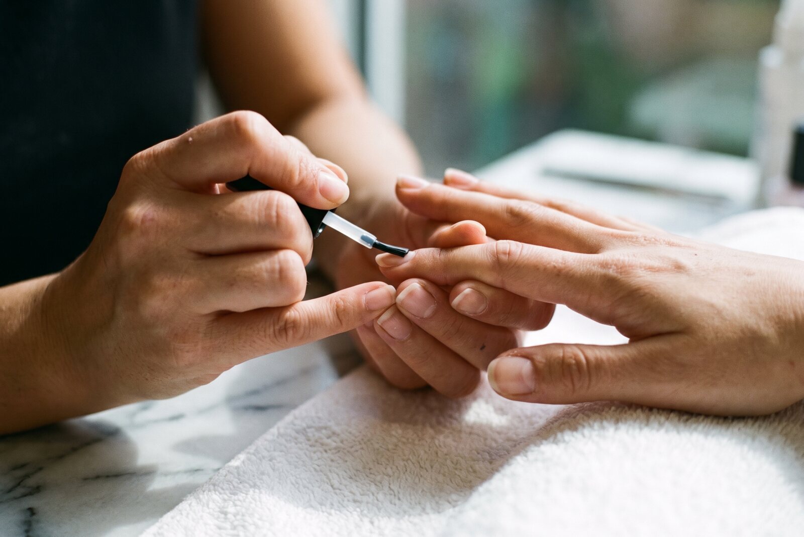 Manicure atendendo uma cliente no salão